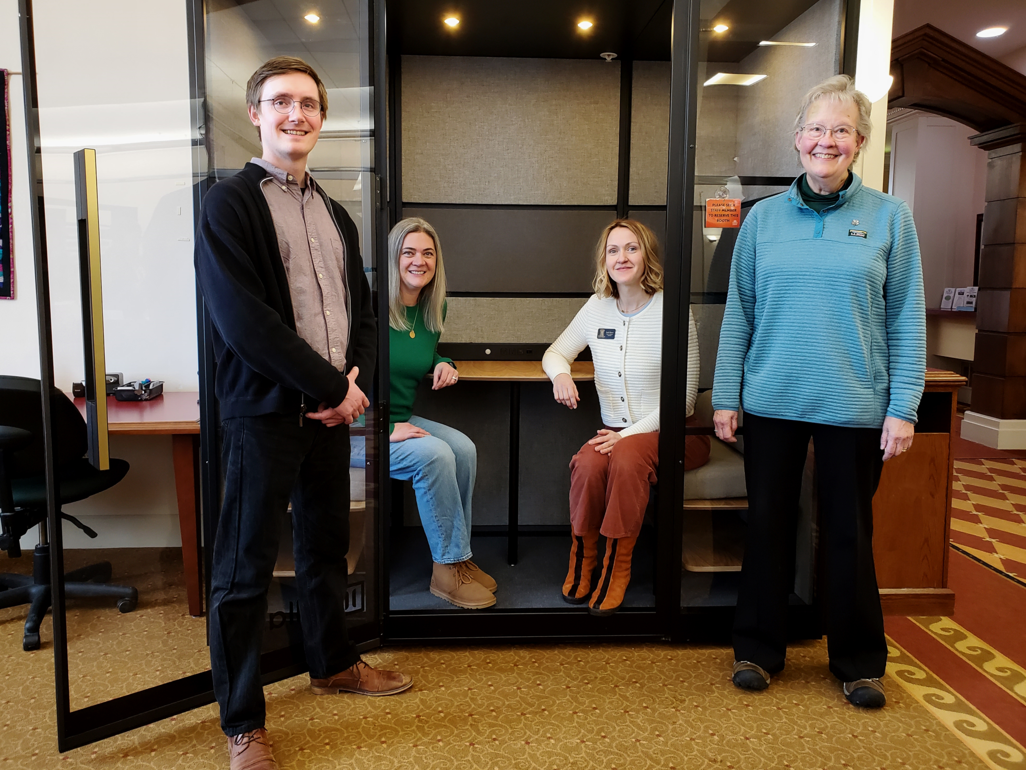 Photo of four adults posed with the library's new private meeting booth