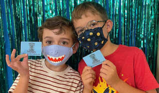 Two young children holding library cards