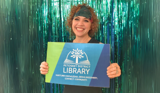 Person holding large library card with tinsel backdrop